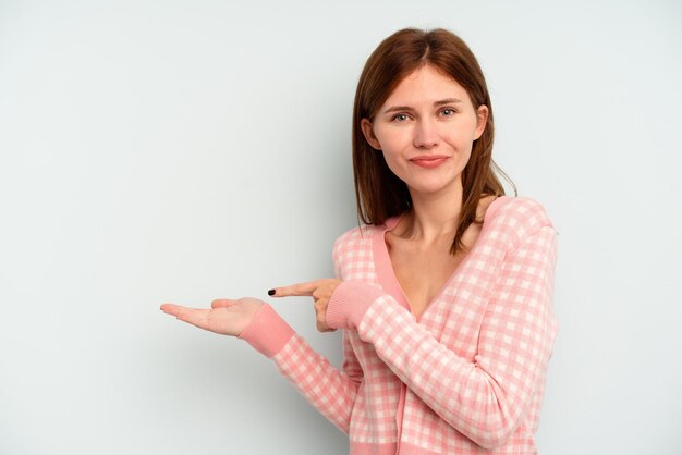 Jonge Engelse vrouw geïsoleerd op blauwe achtergrond opgewonden met een kopie ruimte op de palm.