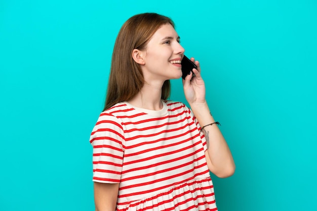 Jonge Engelse vrouw geïsoleerd op een blauwe achtergrond die een gesprek voert met de mobiele telefoon
