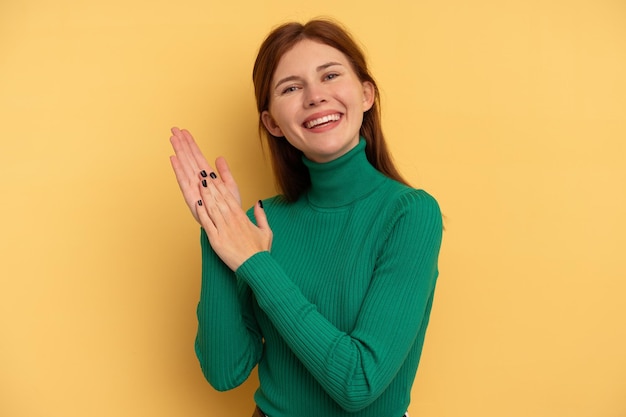 Jonge Engelse vrouw geïsoleerd op een gele achtergrond die zich energiek en comfortabel voelt, zelfverzekerd handen wrijvend.