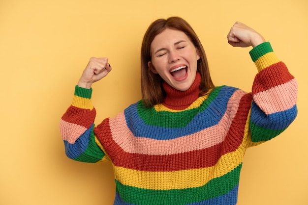 Jonge Engelse vrouw geïsoleerd op gele achtergrond die vuist opheft na een overwinningswinnaarconcept