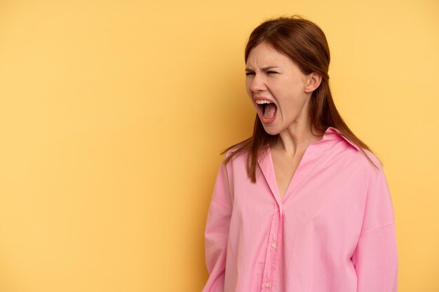 Foto jonge engelse vrouw geïsoleerd op gele achtergrond schreeuwen erg boos, woede concept, gefrustreerd.