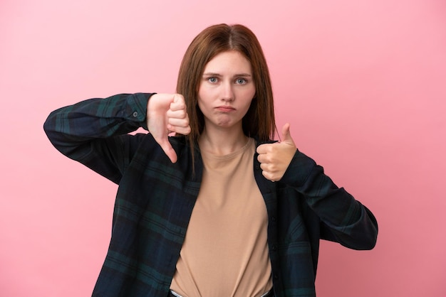 Jonge Engelse vrouw geïsoleerd op roze achtergrond die een goed teken maakt Onbeslist tussen ja of niet?