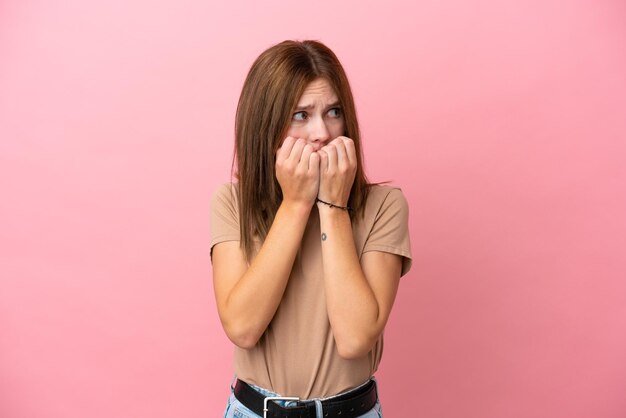 Jonge Engelse vrouw geïsoleerd op roze achtergrond nerveus en bang om de handen in de mond te leggen