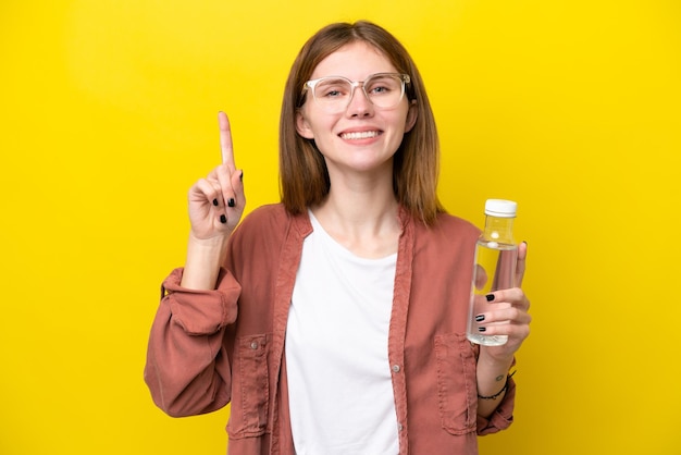 Jonge Engelse vrouw met een fles water geïsoleerd op een gele achtergrond die een geweldig idee benadrukt