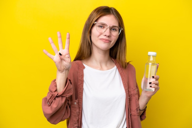 Jonge Engelse vrouw met een fles water geïsoleerd op een gele achtergrond gelukkig en vier tellen met vingers