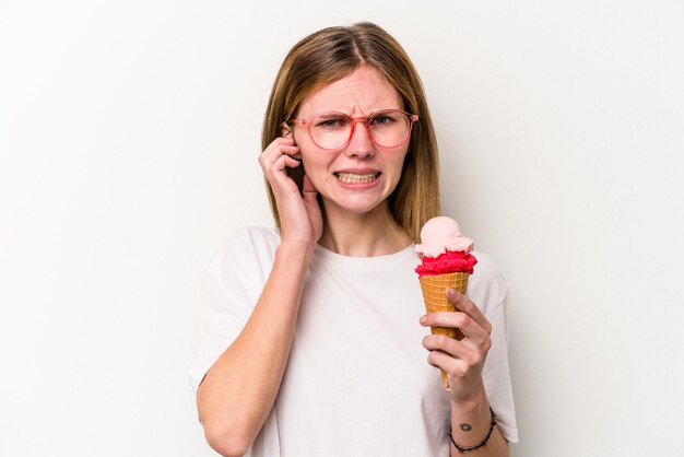 Jonge Engelse vrouw met een ijsje geïsoleerd op een witte achtergrond die oren bedekt met handen