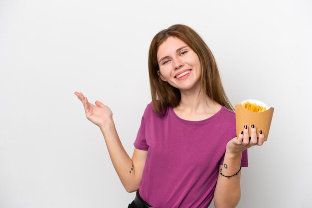 Jonge Engelse vrouw met gefrituurde chips geïsoleerd op een witte achtergrond die de handen naar de zijkant uitstrekt om uit te nodigen om te komen