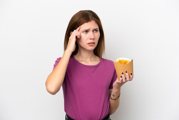 Jonge engelse vrouw met gefrituurde chips geïsoleerd op een witte achtergrond met twijfels en denken