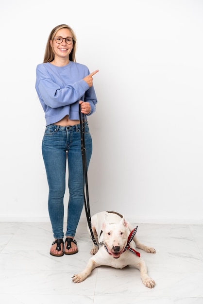 Jonge Engelse vrouw met haar hond geïsoleerd op een witte achtergrond die naar de zijkant wijst om een product te presenteren