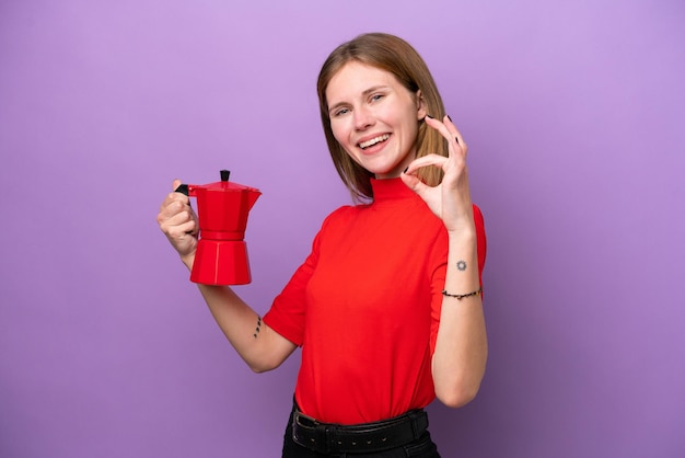 Jonge engelse vrouw met koffiepot geïsoleerd op paarse achtergrond met ok teken met vingers