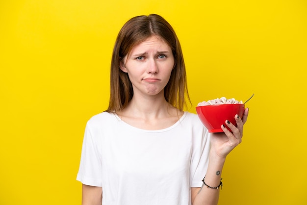 Jonge Engelse vrouw met kopje koffie geïsoleerd op gele achtergrond met droevige uitdrukking