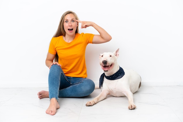 Jonge Engelse vrouw zittend op de vloer met haar hond geïsoleerd op een witte achtergrond met de bedoeling de oplossing te realiseren