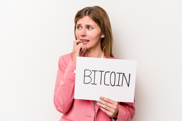 Jonge Engelse zakenvrouw met een bitcoin-plakkaat geïsoleerd op een witte achtergrond ontspannen na te denken over iets dat naar een kopieerruimte kijkt