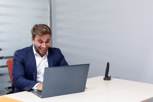 Jonge euforische zakenman die een videogesprek voert op kantoor.