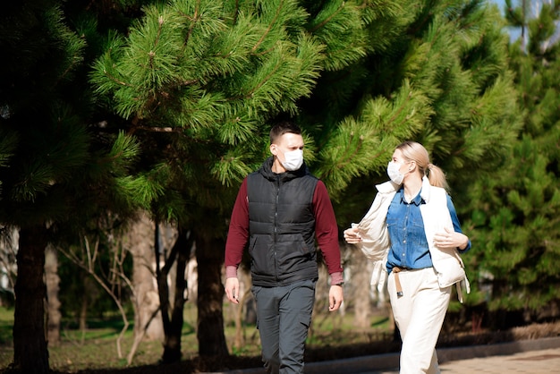 Jonge Europese man en vrouw in een beschermend medisch wegwerpmasker lopen buiten bang voor het gevaarlijke NCoV 2019 influenza coronavirus gemuteerd en verspreid in China.