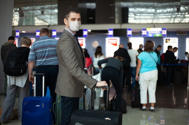 Jonge europese man in beschermend medisch masker op de luchthaven. bang voor gevaarlijk covid-19 influenza coronavirus