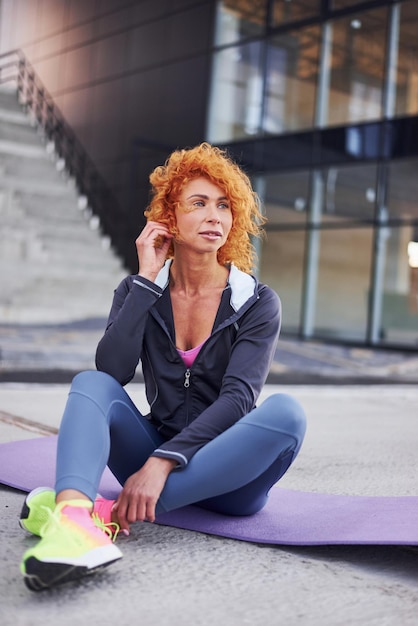 Jonge Europese roodharige vrouw in sportieve kleding die buiten zit