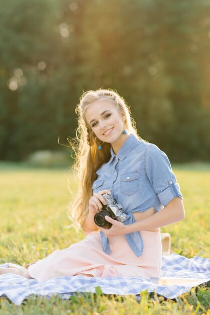 Jonge Europese toerist lacht vrolijk met vintage camera in de natuur