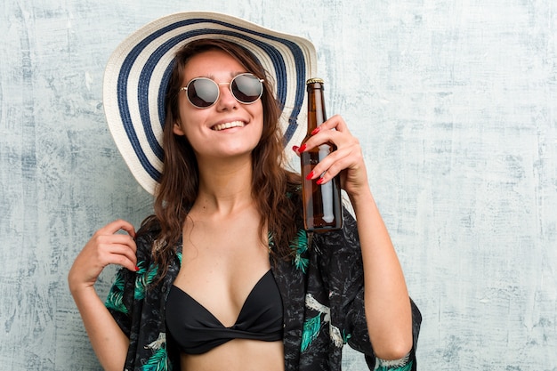 Jonge Europese vrouw die bikini draagt en een bier drinkt