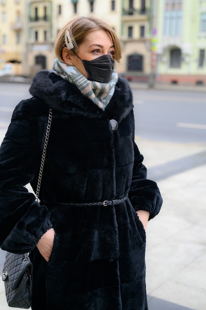 Jonge Europese vrouw in beschermend wegwerp medisch zwart masker in stad buiten. conceptbescherming van gevaarlijk 2019-nCoV influenza coronavirus, gemuteerd en verspreid in China. verticale foto