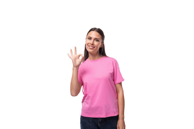 Jonge europese vrouw met zwart haar in een roze t-shirt heeft een voorstel op een witte achtergrond met kopie