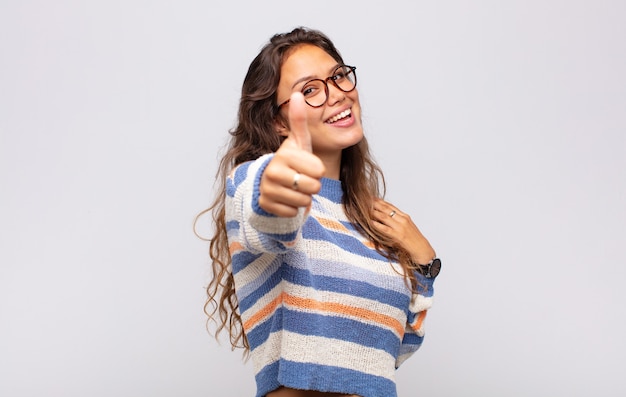 jonge expressieve vrouw met een bril die zich voordeed op een witte muur