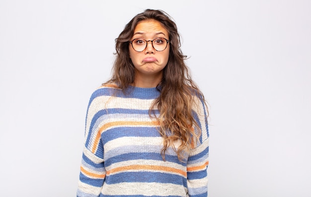 jonge expressieve vrouw met een bril die zich voordeed op een witte muur