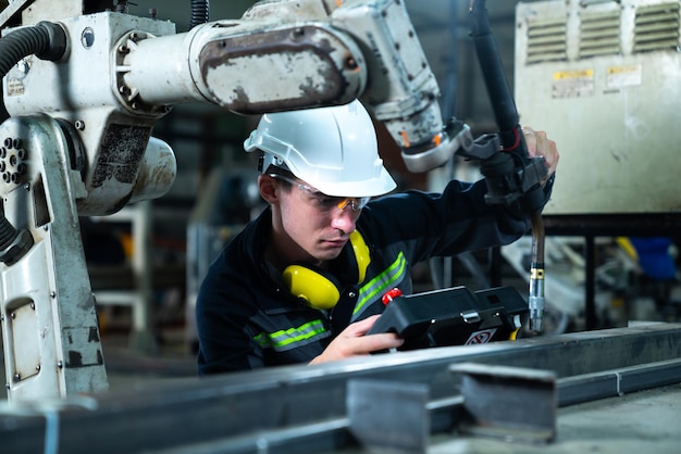 Jonge fabrieksarbeider die werkt met een bedreven robotarm