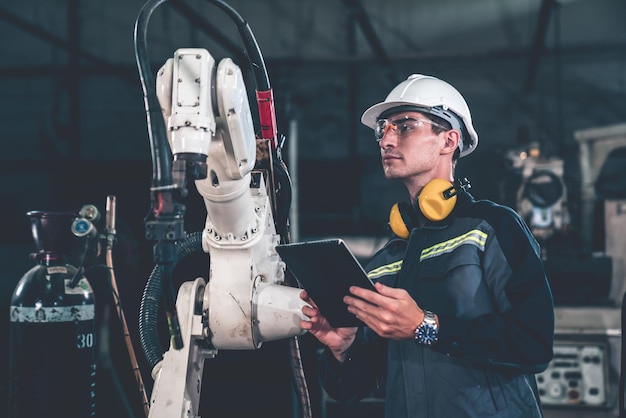 Jonge fabrieksarbeider die werkt met een bedreven robotarm