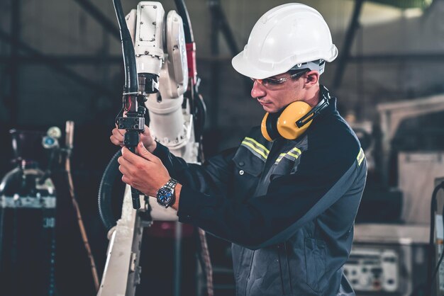 Jonge fabrieksarbeider die werkt met een bedreven robotarm