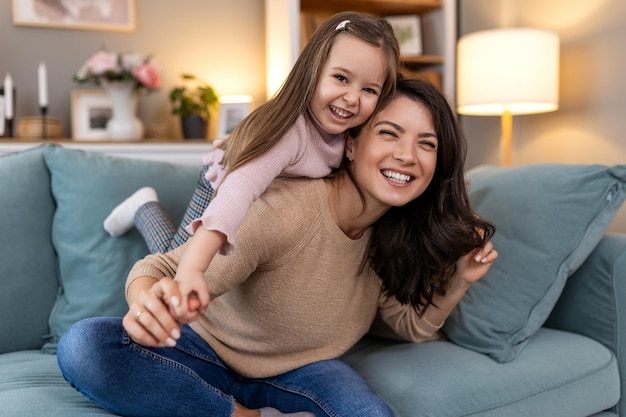 Jonge familie knuffel en portret van kind met moeder moeder of mama band ontspannen en genieten van kwaliteitstijd samen Liefde gelukkig gezin en vrouw met kind meisje glimlach zorg of lounge op huis woonkamer bank