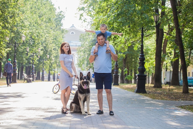 Jonge familie moeder, vader en zoon op een wandeling met een herdershond op de stad