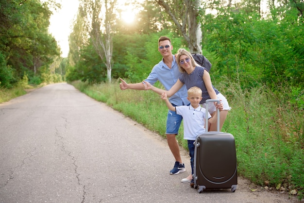 Foto jonge familie reiziger kink in de kabel wandelen op lege weg.