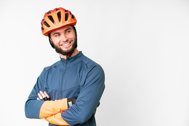 Jonge fietser man over geïsoleerde witte achtergrond met armen gekruist en gelukkig