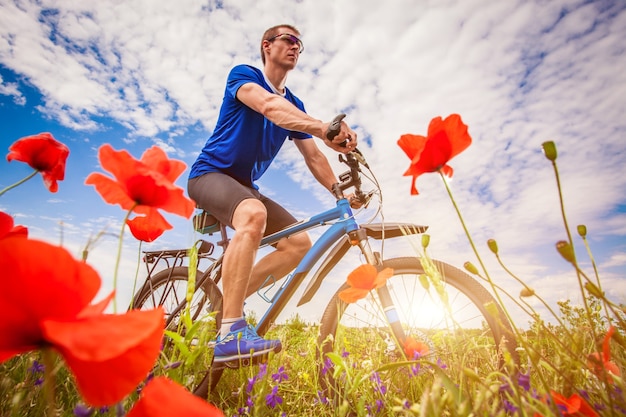 Jonge fietser rijdt op papaverveld bij zonsondergang