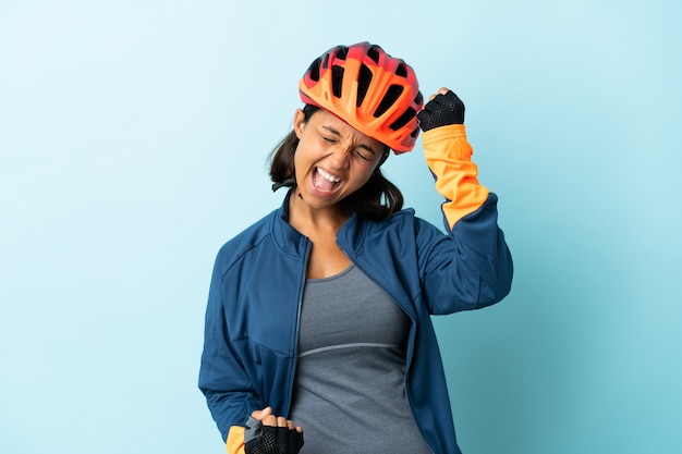 Jonge fietser vrouw geïsoleerd op blauw een overwinning vieren