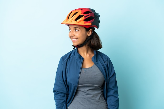 Jonge fietser vrouw geïsoleerd op blauw op zoek naar de kant en lachend