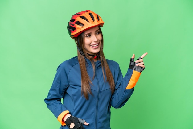 Jonge fietser vrouw over geïsoleerde chroma key achtergrond wijzende vinger naar de zijkant en een product presenteren