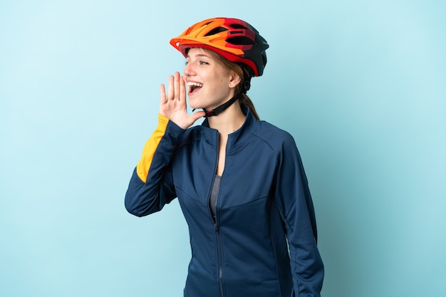 Jonge fietservrouw die op blauwe muur wordt geïsoleerd die met wijd open mond aan de kant schreeuwt