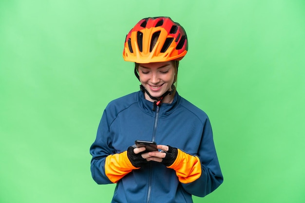 Jonge fietservrouw over geïsoleerde chroma key-achtergrond die een bericht verzendt met de mobiel