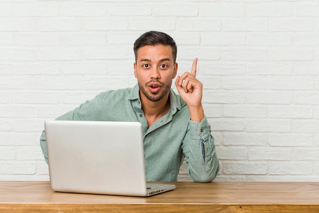 Jonge filipijnse mensenzitting die met zijn laptop werken die een idee hebben