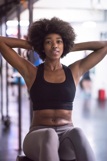 jonge fit Afro-Amerikaanse vrouw doet sit-ups in de fitnessstudio in de sportschool. Buikoefeningen Sit up