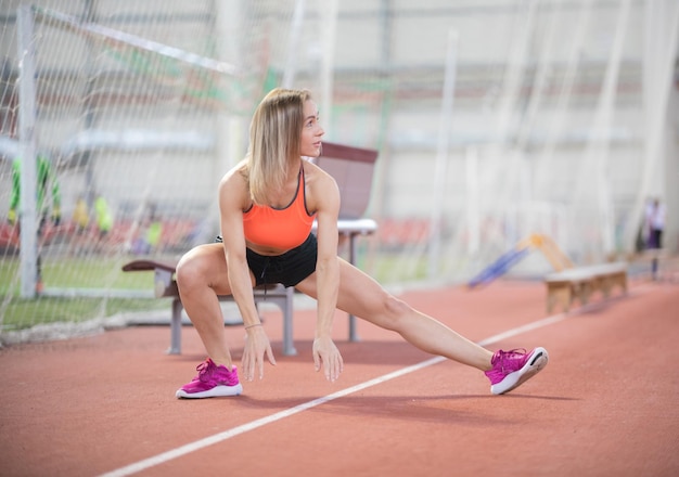 Foto jonge fit atletische vrouw die zich uitstrekt en zich voorbereidt om te rennen