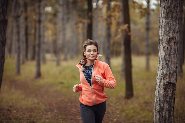 Jonge fit vrouw in sportkleding loopt langs bospad