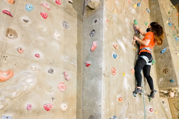 Jonge fit vrouw klimmen op indoor rotswand.