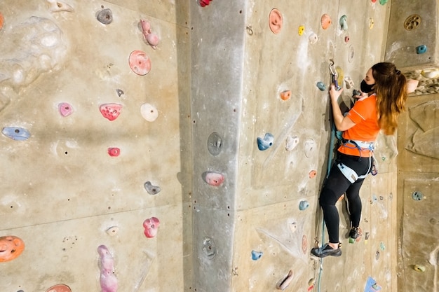 Jonge fit vrouw klimmen op indoor rotswand.