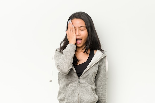 Jonge fitness Chinese vrouw die pret heeft die de helft van gezicht behandelt met palm.