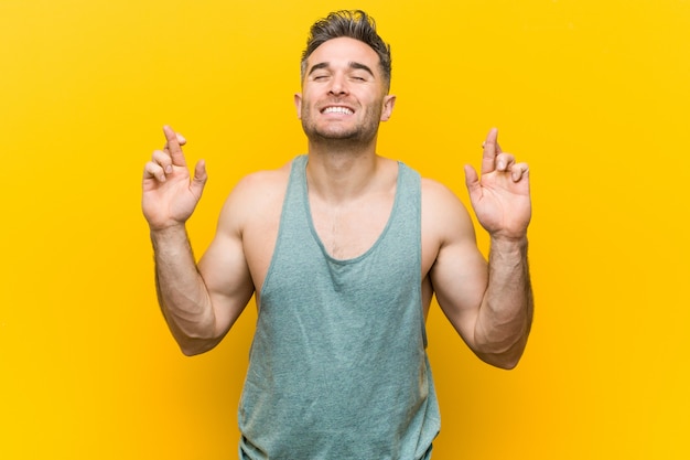 Jonge fitness man kruising vingers voor het hebben van geluk