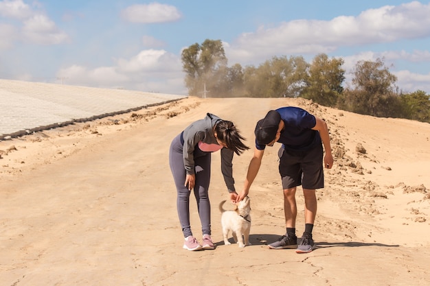 Jonge fitness paar aaien hun kleine hond in het zand.