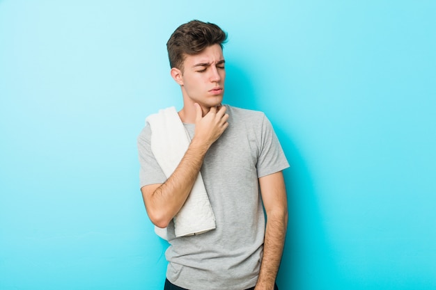 Jonge fitness tiener man lijdt pijn in de keel als gevolg van een virus of infectie.